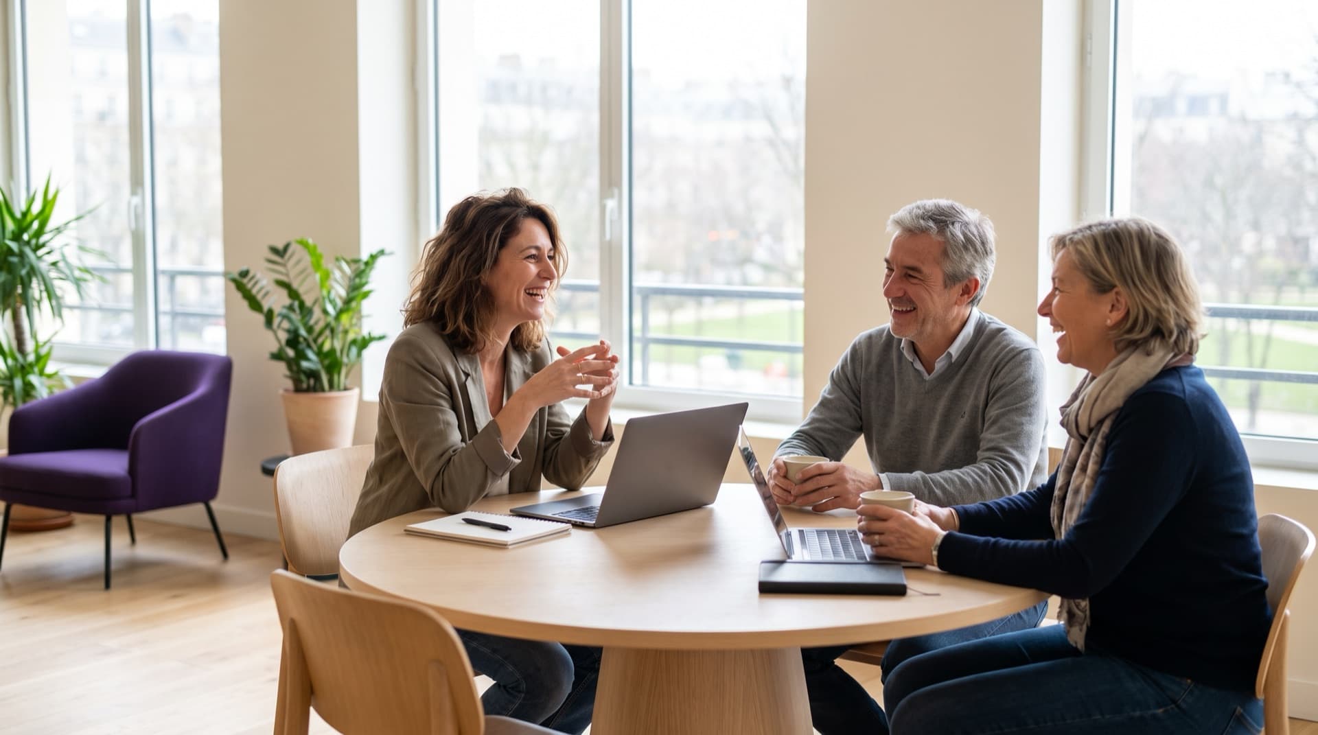 Une conseillère en gestion de patrimoine échange avec un couple dans un bureau lumineux